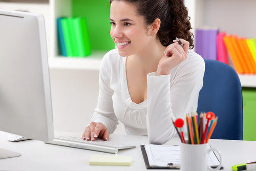 Cheerful young woman using computer at home